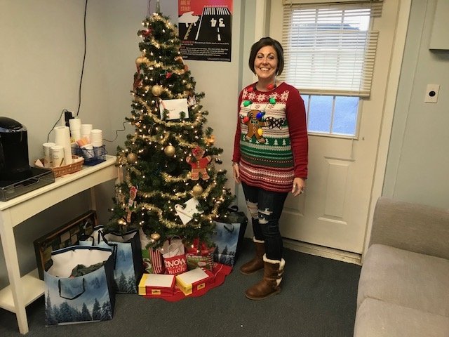 Ocean Aviation employee standing by Christmas tree and gifts